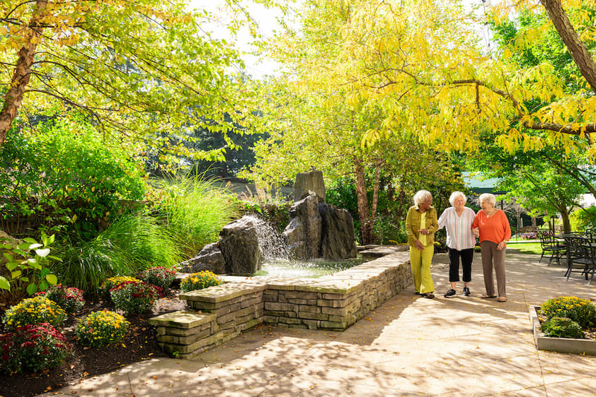 Group of seniors walking on patio near waterfall